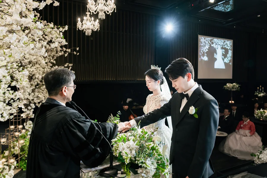주례자 앞에서 두 손을 맞잡는 신랑신부의 예식 장면