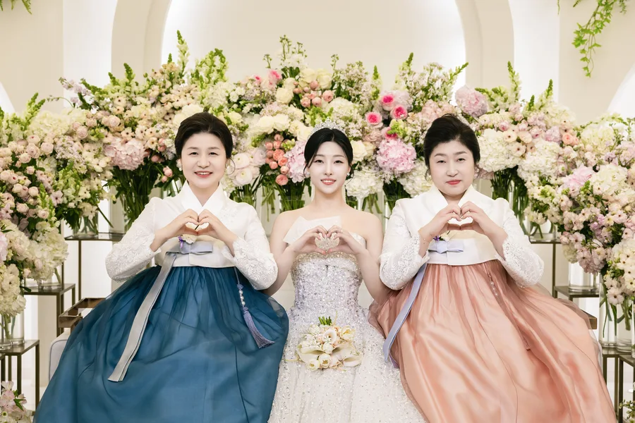 하트 손모양을 만든 신부와 한복 입은 두 어머니의 기념사진
