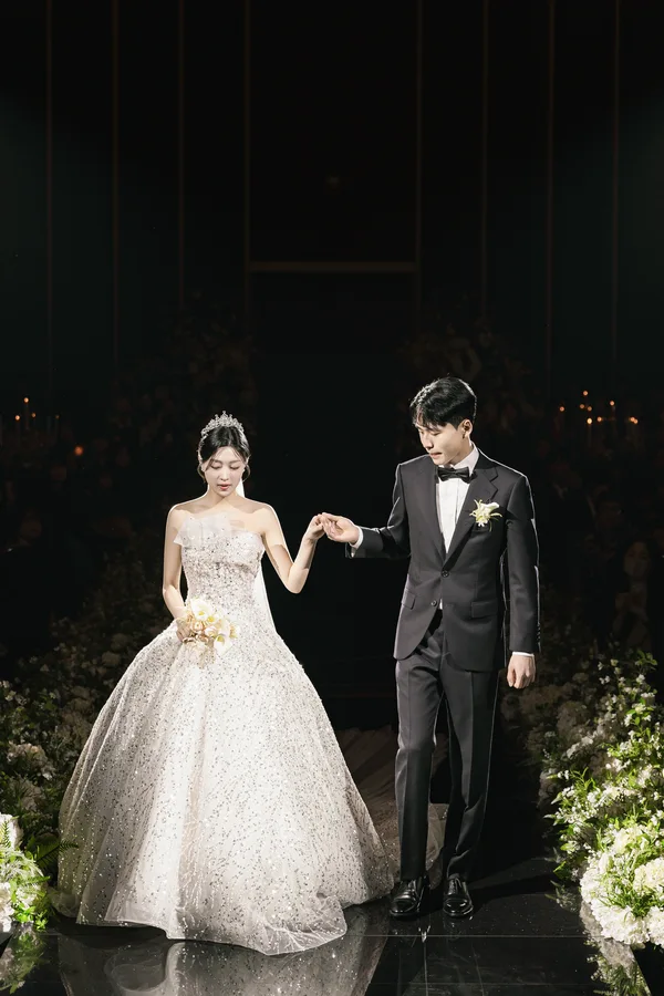 신랑과 손을 맞잡고 버진로드를 걸어 나가는 신랑신부 뒷모습