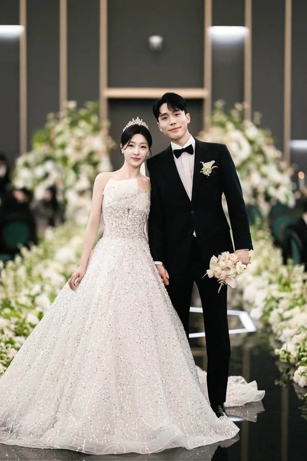 회색 골드 톤 벽 앞에서 손잡고 나란히 선 신랑신부 정면 전신컷